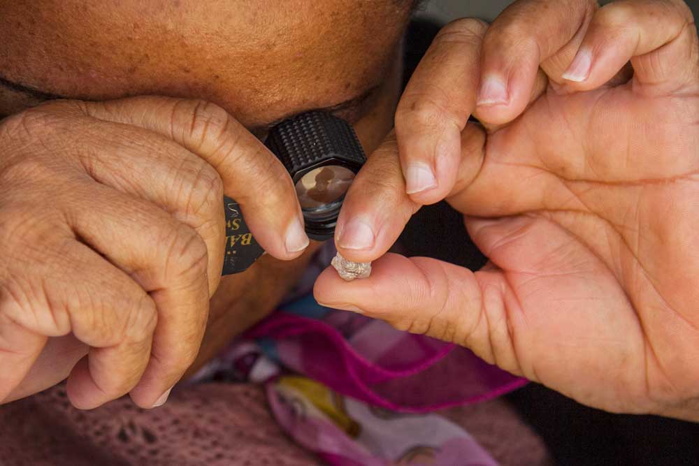Female diamond inspector in Botswana examining gemstone through microscope