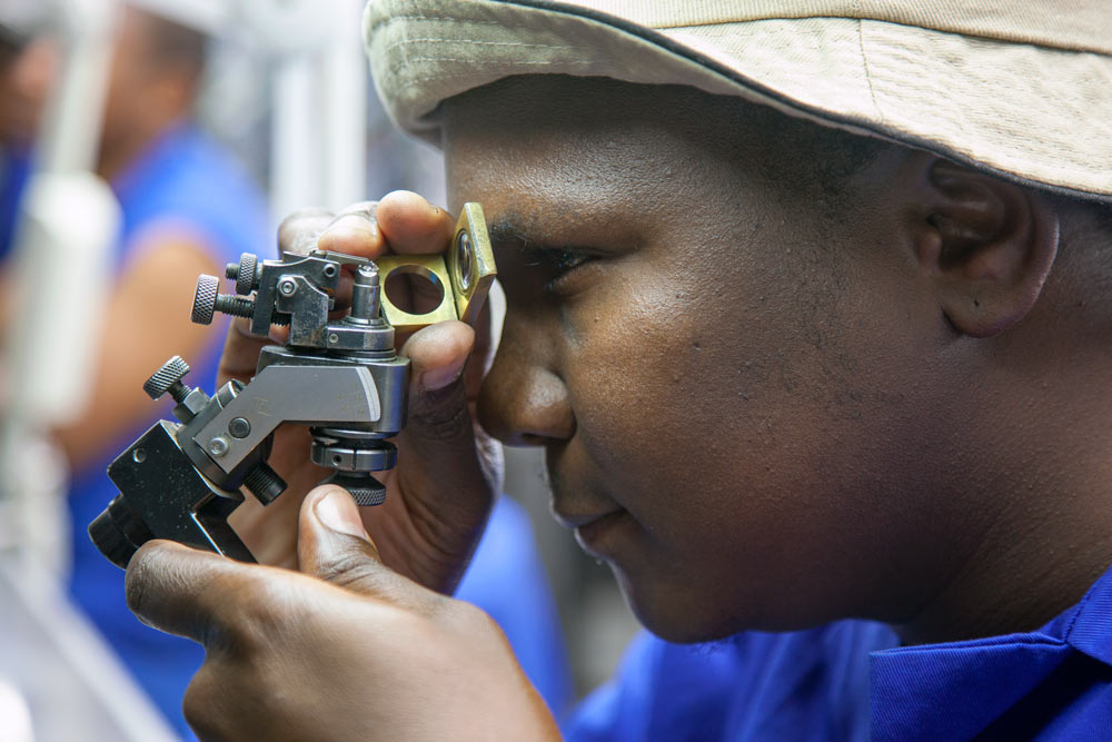 Diamond polishing craftsman using precision optical equipment at Steinmetz Botswana