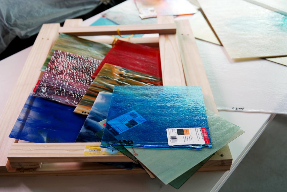 Colourful glass sheets and craft materials arranged on workshop table