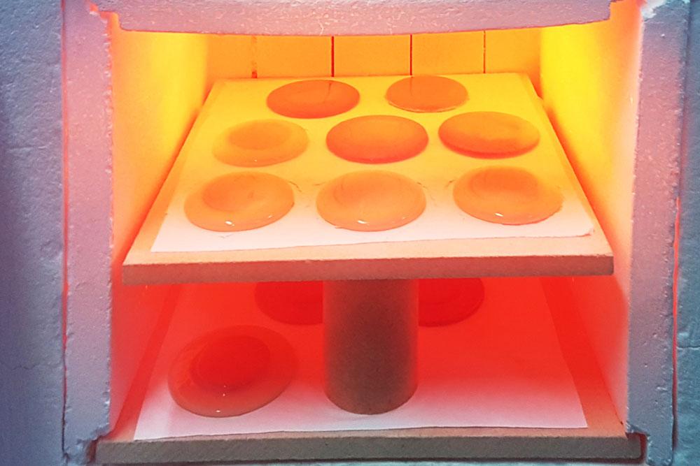 Glass kiln interior showing molten glass pieces being fired at high temperature