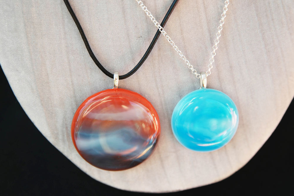 Two handmade glass pendant necklaces in turquoise and orange showing finished jewellery from workshop project