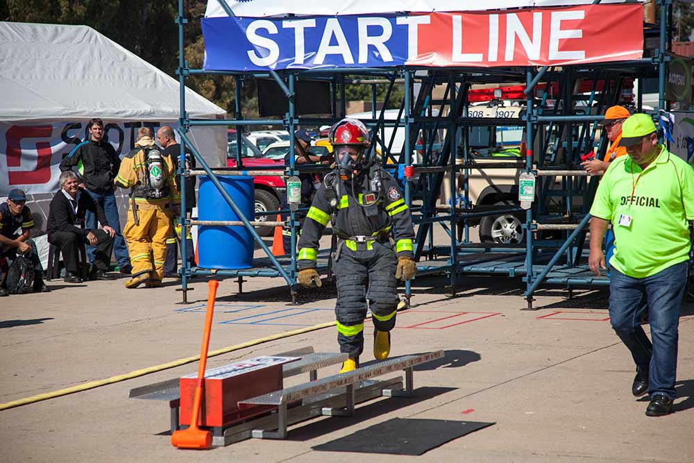 Firefighter in full protective gear navigating obstacle course during timed rescue challenge