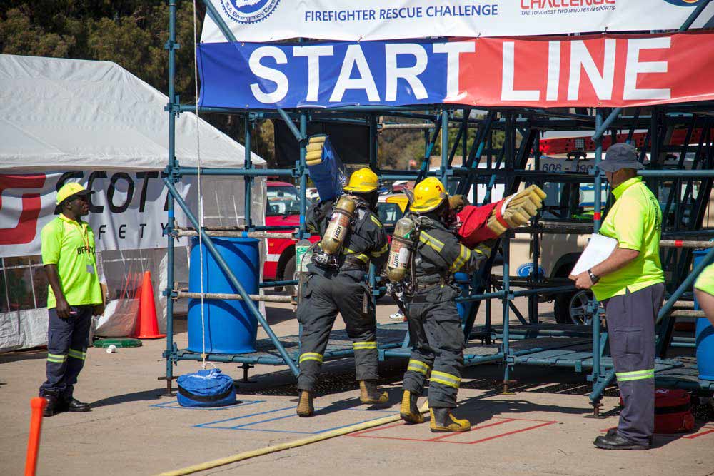 Firefighters in full protective gear and breathing apparatus at start line of rescue challenge competition
