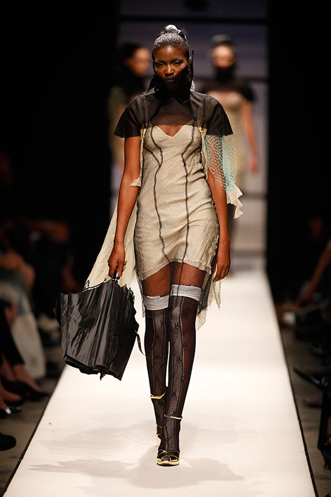 Model wearing contemporary structured dress with deconstructed design on SA Fashion Week runway