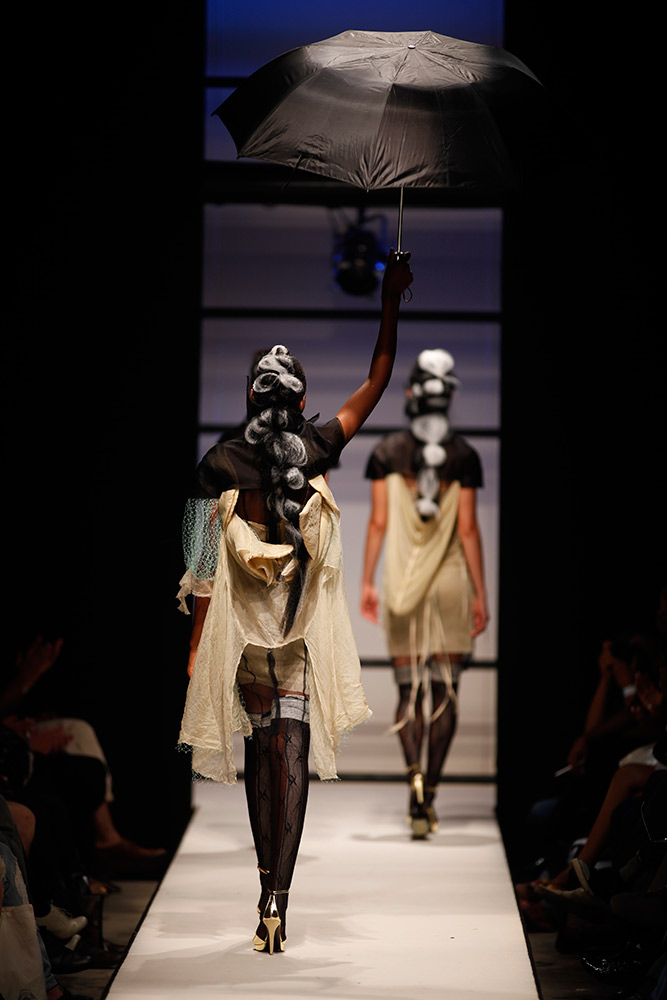 Dramatic fashion runway photography with model holding umbrella in theatrical presentation