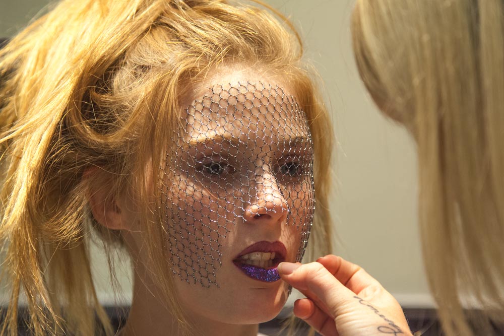Dramatic beauty makeup with crystal mesh veil and bold lips backstage at fashion show
