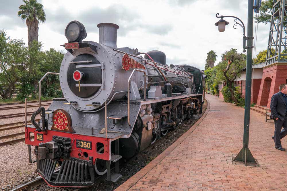 A vintage Rovos Rail luxury steam locomotive at a station platform
